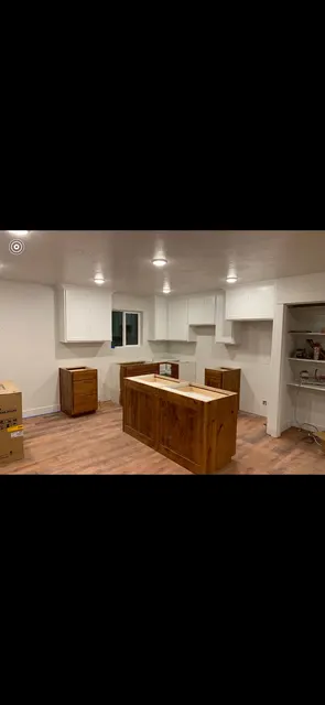 White upper cabinets and wood lower cabinets and island during kitchen installation.