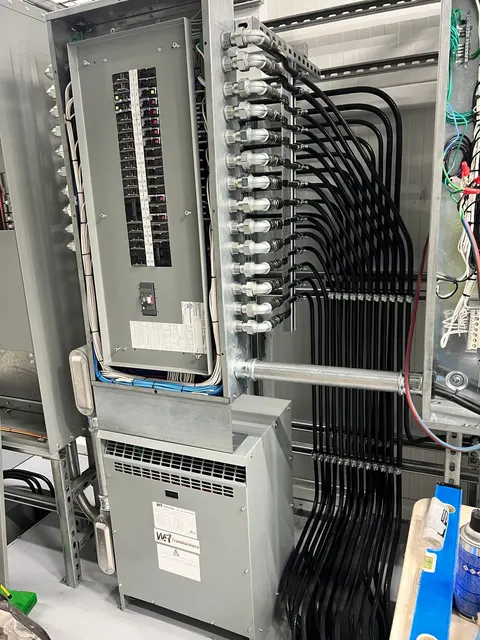 Electrical panel, transformer enclosure, and organized flexible conduit runs.